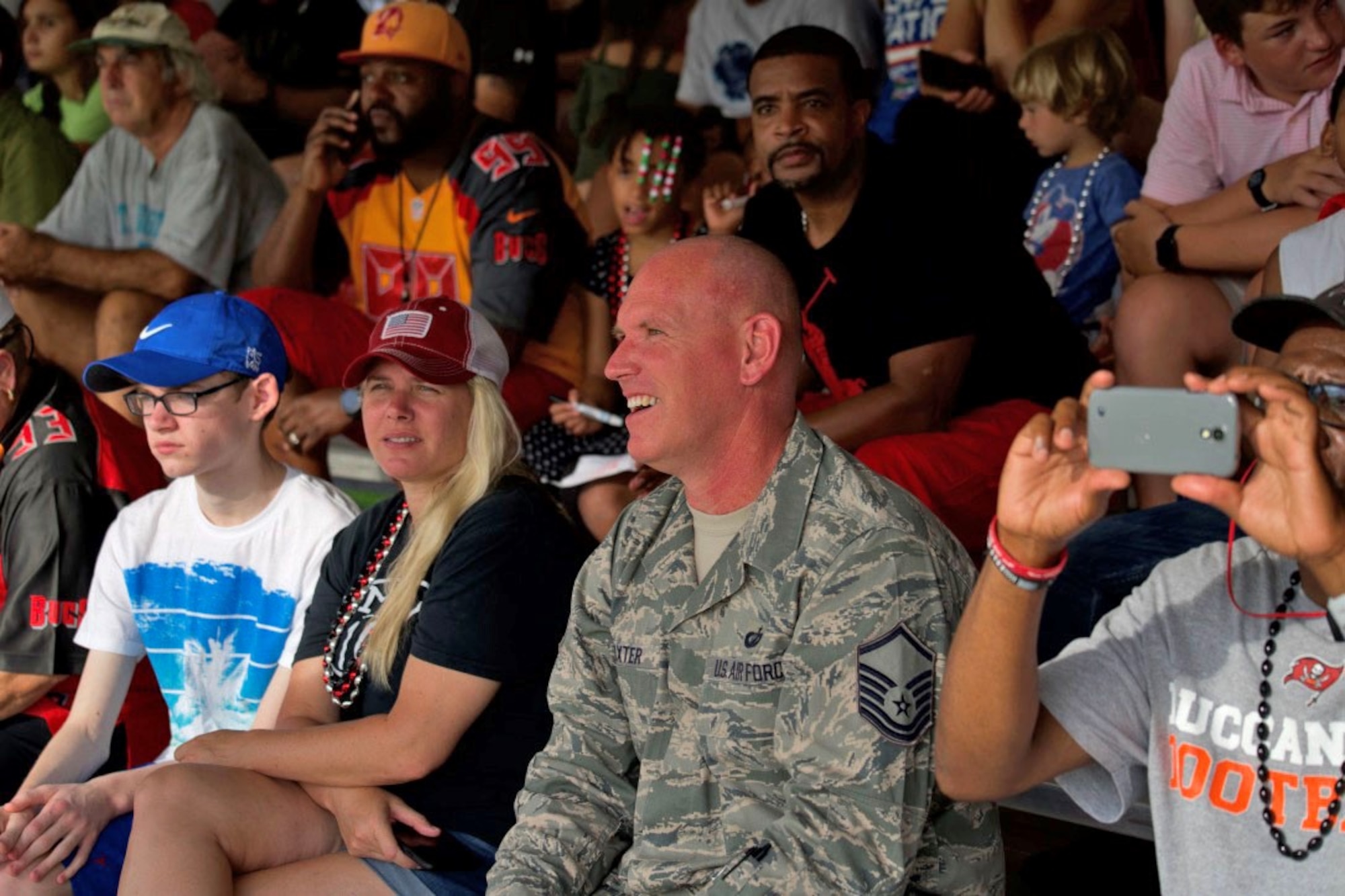 Service members and families sit along the sidelines to watch the Tampa Bay Buccaneers Training Camp on August 5 at the AdventHealth Training Center in Tampa. Every year the Tampa Bay Buccaneers have a Military-Day Training Camp for all military, retired or veteran service members and dependents. (U.S. Air Force photo by Senior Airman Alexis Suarez) 190805-F-CG206-0023