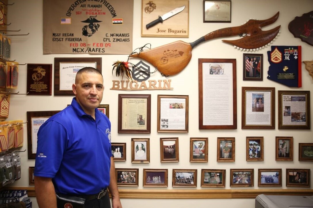 Gunnery Sergeant Jose Bugarin stands next to his wall of accomplishments in his office at 1st Marine Corps District (1MCD), Garden City, New York, July 16, 2019. As his latest accomplishment, Bugarin brought the 1ST MCD food establishment, Tun Tavern, to earn its first Marine Corps Community Service’s Food and Hospitality Excellence Award by placing 12th overall. (U.S. Marine Corps Photo by Sgt. Paul T. Williams III)