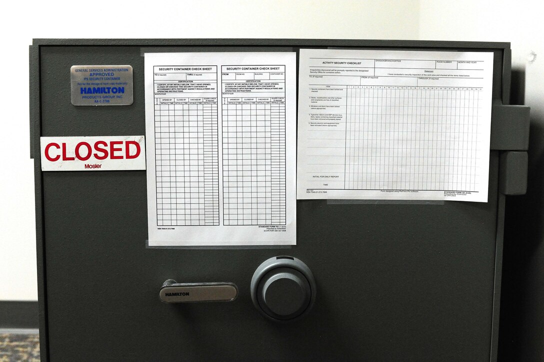 A safe bears a magnet with the word “CLOSED.”  Checklists also adorn the safe.