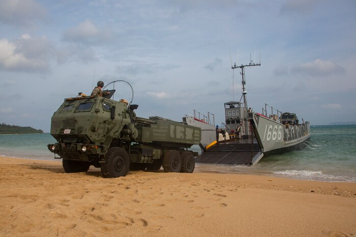 A landing craft, utility assigned to the amphibious transport dock ship USS Green Bay, lowers its ramp to unload a High Mobility Artillery Rocket System from 3rd Battalion, 12th Marine Regiment, 3rd Marine Division, as part of a simulated amphibious raid, at Kin Blue, Okinawa, Japan, Aug. 14, 2019. This simulated amphibious raid marks the first time that HIMARS have been inserted by landing craft, utility, demonstrating the Marine Air-Ground Task Force’s ability to conduct combined-arms maneuver from amphibious shipping.