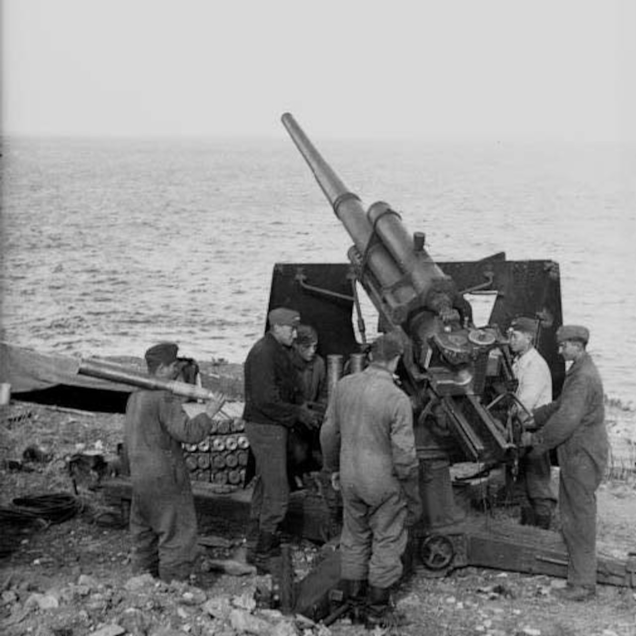 Men stand around howitzer.