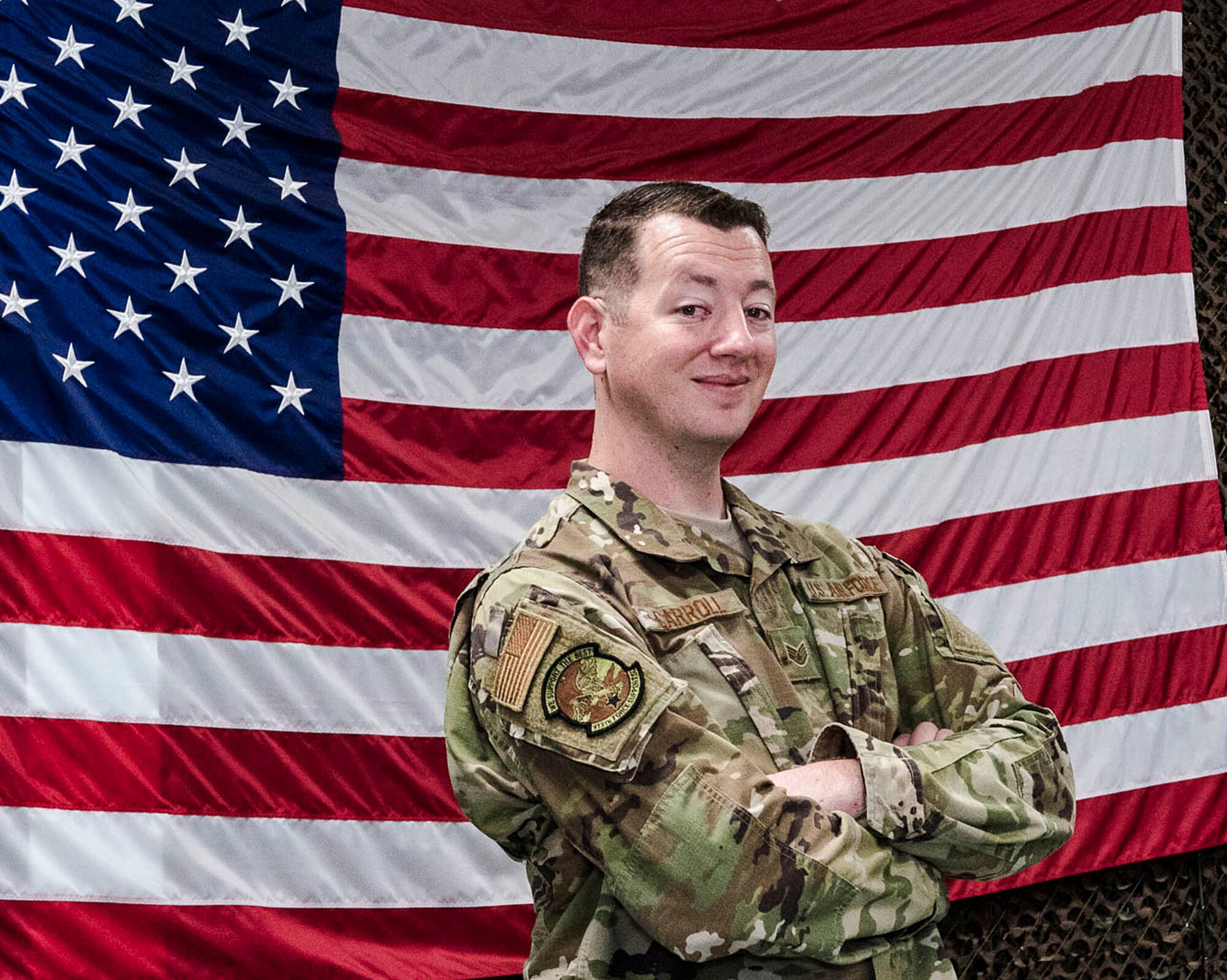 Airman poses in front of U.S. flag for Airman of the week.
