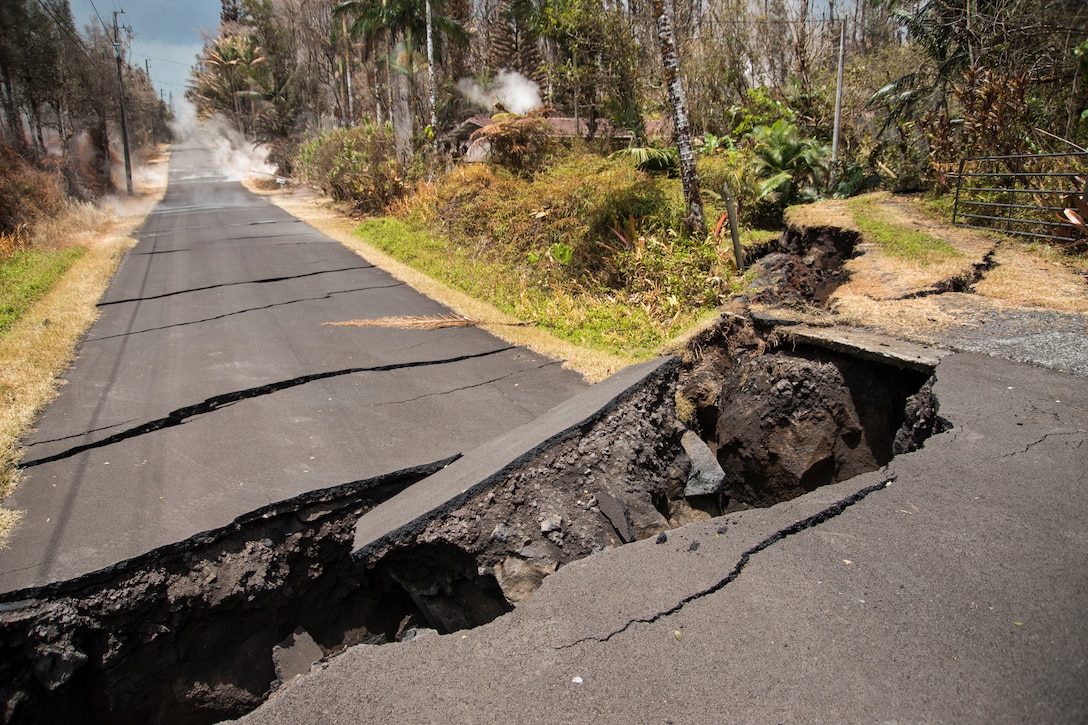 A huge chasm crosses a small road.
