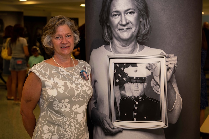 A woman poses next to a black and white photo of herself.