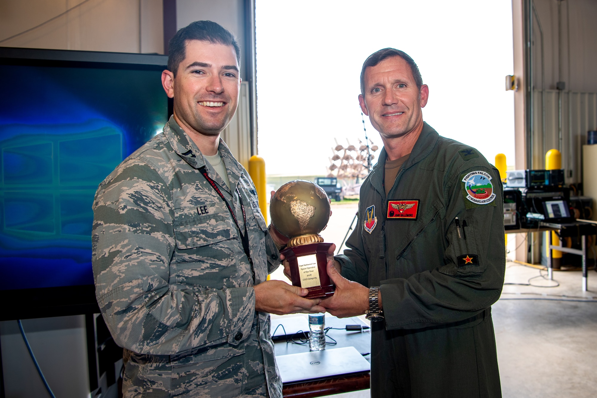 Col. John Gallemore, 57th Adversary Tactics Group commander, right, presents the U.S. Air Force Space Operator of the Year, company grade officer category, award to Capt. Nathaniel Lee, 527th Aggressor Squadron chief of future operations, at the 527th SAS barn, Schriever Air Force Base, Colorado, Aug. 15, 2019. In his role, Lee oversees and coordinates the unit’s threat replication program, which mimics threats to the United States, allied space systems and their critical nodes. (U.S. Air Force photo by Kathryn Calvert)