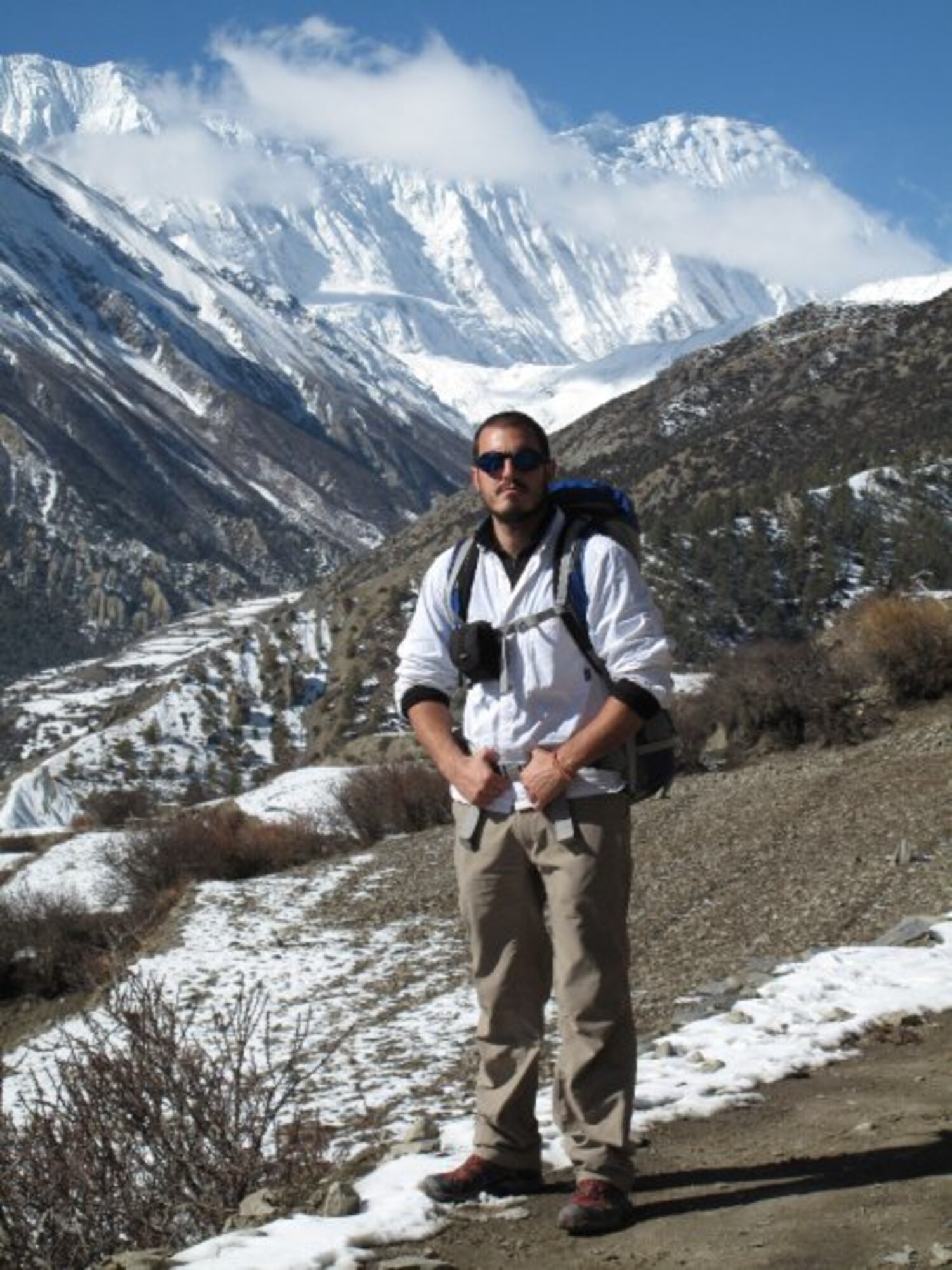 Airman stands on mountains in hiking gear.