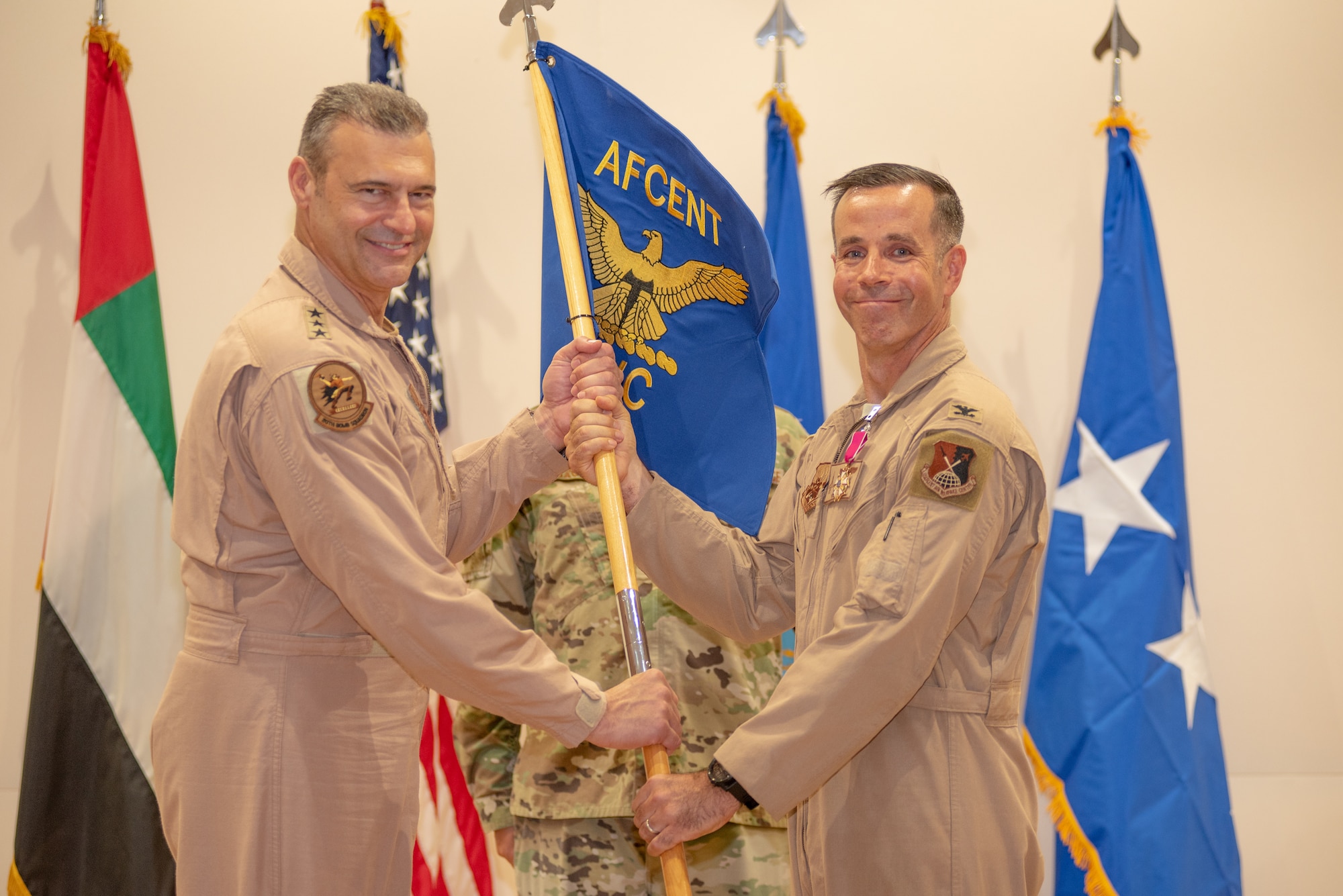 Col. Jason Hokaj relinquishes command of the Air Warfare Center by handing the guidon to Lt. Gen. Joseph T. Guastella, U.S. Air Force Central Command commander, June 19, 2019, at Al Dhafra Air Base, United Arab Emirates.