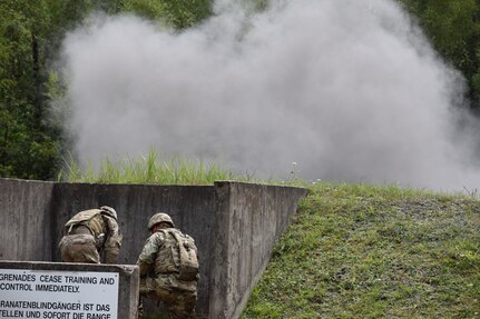 Master Sgt. Carlos Garcia, 2500th DLD acting sergeant major, and Sgt. Mallory Valle, medic, duck below the barrier after throwing a live hand grenade during a familiarization and qualification range Aug. 16 at Grafenwoehr Training Area in Germany.