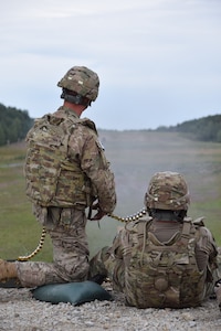 Staff Sgt. Ladislav Pecsuk, 2500th Digital Liaison Detachment fires operations sergeant, serves as assistant gunner and feeds the ammo for Sgt. Wesley Cyrus, chemical noncommissioned officer, who fires the .50-caliber weapon system during a familiarization and qualification range Aug. 15 at Grafenwoehr Training Area in Germany. The 2500th DLD is conducting basic warrior tasks and familiarizing themselves with battlefield enablers during annual training.