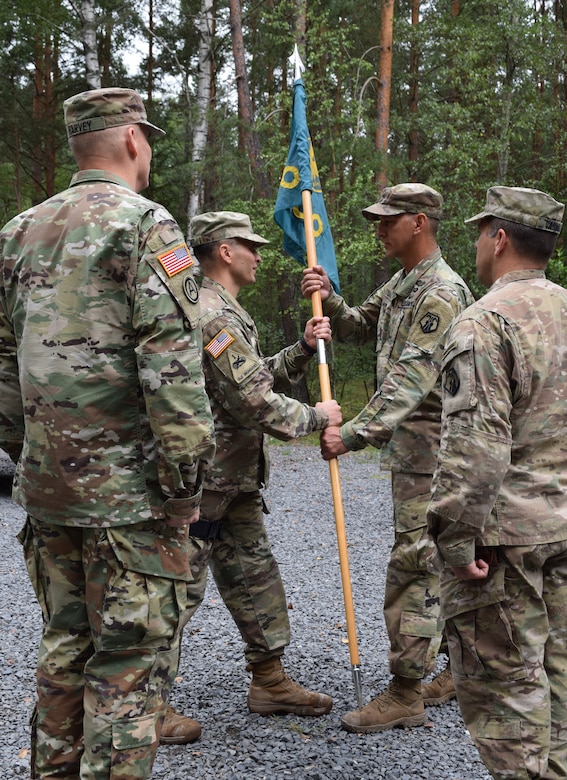 Incoming commander Col. Gregory Gimenez returns the colors to Master Sgt. Carlos Garcia, completing the passing of the colors during the 2500th Digital Liaison Detachment change of command ceremony Aug. 17 at Camp Normandy, Grafenwoehr, Germany. Gimenez takes over from Col. Christopher Varhola.