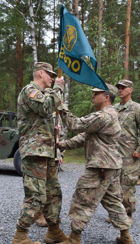 Col. Christopher Varhola passes the 2500th Digital Liaison Detchment colors to Brig. Gen. Michael T. Harvey symbolizing his relinquishment of command during a change of command ceremony Aug. 17 at Camp Normandy, Grafenwoehr, Germany. After three years in the position, Varhola passed command of the 2500th DLD to Col. Gregory Gimenez.