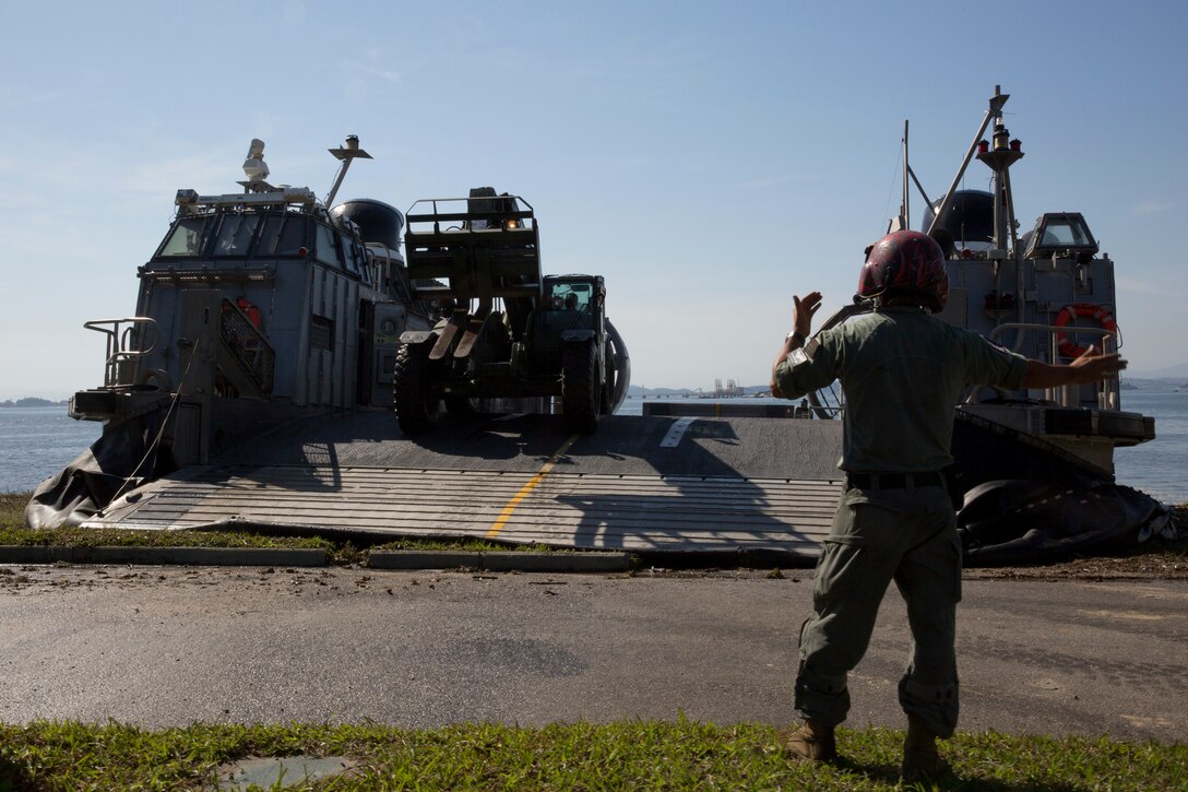 A U.S. Navy beach master unloads heavy equipment from a U.S. Navy landing craft.