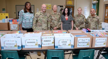 (From left) Lorraine Harper, a 187th Medical Battalion civilian employee; Michelle Ayala, Briscoe Elementary School social worker; Lt. Col. Paul Lang, commander, 187th MED BN; Maj. Debra Stone, MSW executive officer; Jennifer Emerson, Briscoe Elementary School principal; 2nd Lt. Jamie Webb, MSW student, 1st Sgt. Roman De Vega, Company A, 187th MED BN; and Carlos Flores, 187th MED BN civilian employee, pose in front of more than $10,000 worth of donated school supplies Aug. 8.