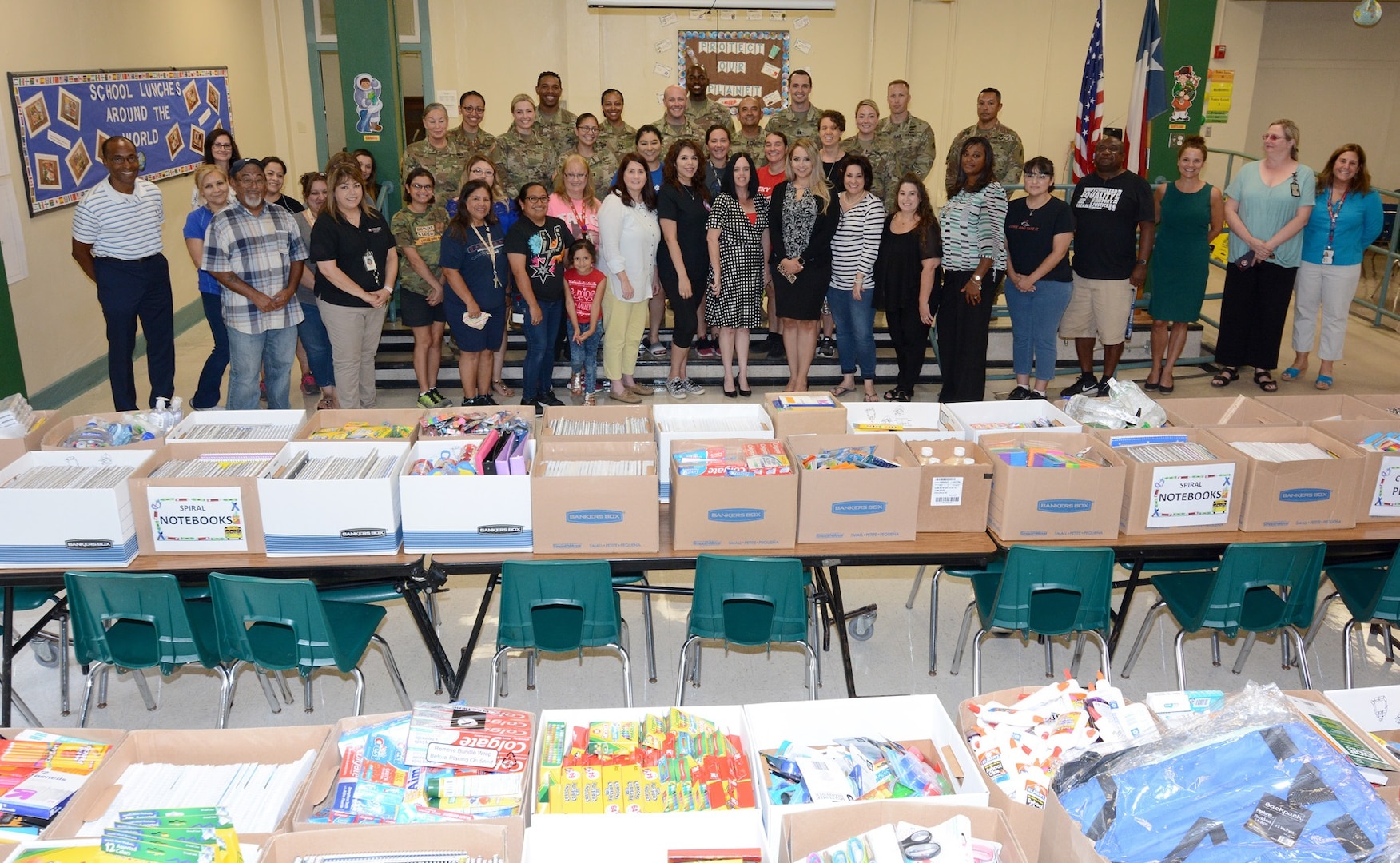 Briscoe Elementary School staff and Soldiers from the 187th Medical Battalion pose in front of more than $10,000 worth of donated school supplies Aug. 8.