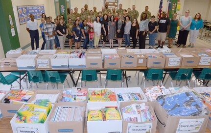 Briscoe Elementary School staff and Soldiers from the 187th Medical Battalion pose in front of more than $10,000 worth of donated school supplies Aug. 8.