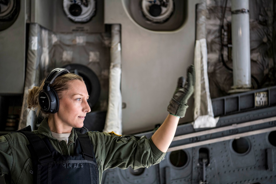 An airman gestures aboard an aircraft.