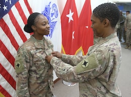 Spc. Ravan Lee, 184th Sustainment Command, is pinned the rank of sergeant by her step-mother, Lt.  Col. Annie Merle Lee, 184th Sustainment Command, at Camp Arifan, Kuwait, Aug. 14, 2019.