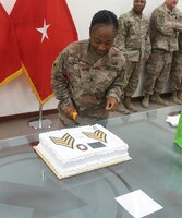Sgt. Ravan Lee, 184th Sustainment Command, cuts a slice out of the cake she received for being promoted to the rank of sergeant at Camp Arifan, Kuwait, Aug. 14, 2019.