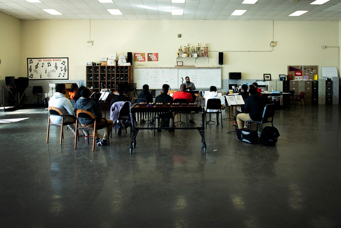 Students in a high school music class huddle around the teacher.