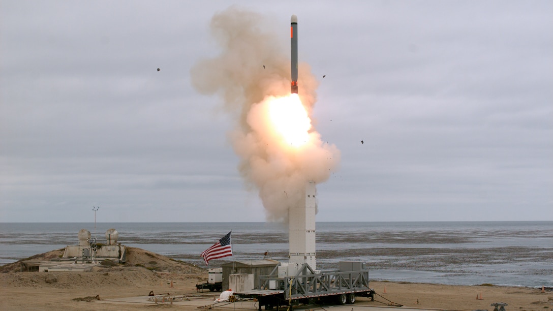 A missile launches on a beach.