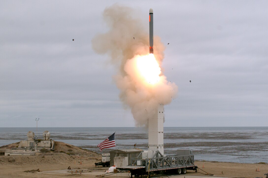 A missile launches on a beach.