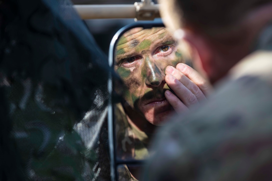 A soldier applies paint to his face.