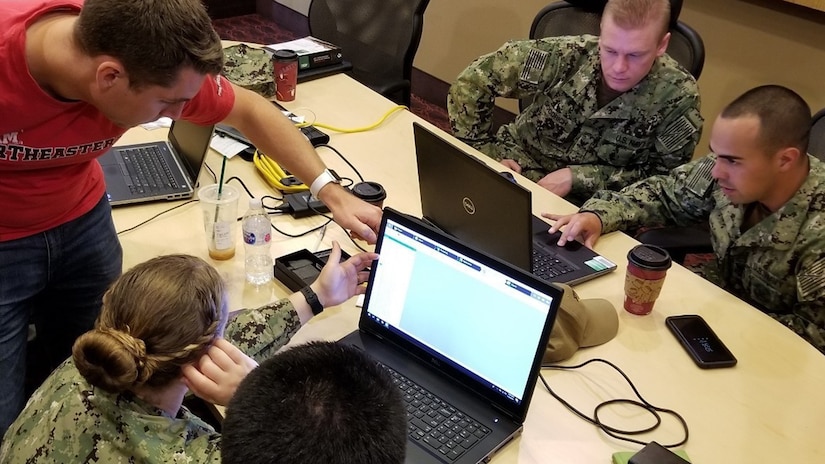 People sit around laptops chatting.