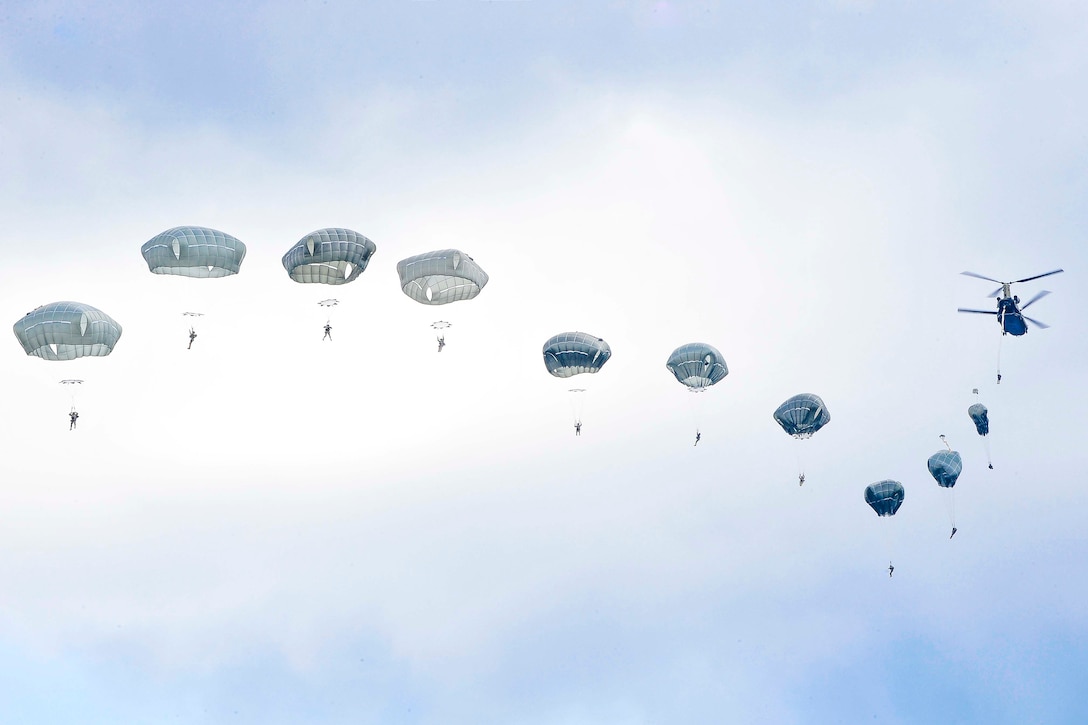 Paratroopers  jump out of an aircraft in a row.