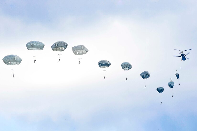 Paratroopers  jump out of an aircraft in a row.