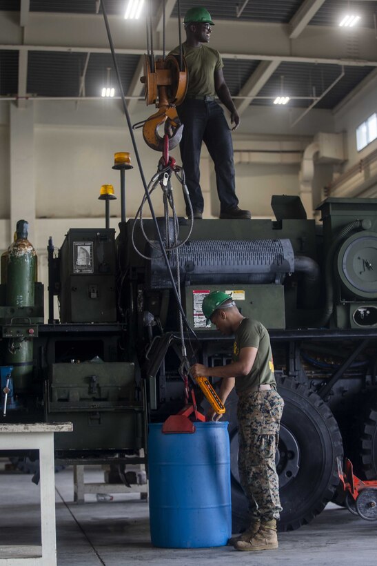 U.S. Marine Corps Cpl. Alexander Roserieerden, bottom, and Lance Cpl. Marcelius Williams prepare to lift a barrel of radiator fluid during preventative maintenance on Camp Kinser, Okinawa, Japan, August 16, 2019. The Marines with Motor Transportation Maintenance Company regularly conduct preventative maintenance on vehicles to ensure serviceability. Roserieerden, a native of the U.S. Virgin Islands, is a motor transportation technician with MTM Co., 3rd Maintenance Battalion, Combat Logistics Regiment 35, 3rd Marine Logistics Group. Williams, a native of Detroit, Michigan, is a motor transportation technician with MTM Co., 3rd Maint. Bn., CLR-35, 3rd MLG. (U.S. Marine Corps photo by Lance Cpl. Armando Elizalde)