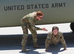 Sgt. James Harty, a CH-47 Chinook helicopter repairer with the 2d Battalion, 501st Aviation Regiment, 1st Armored Division, playfully puts hit older sister Spc. Kelsey Harty, a paralegal specialist with the 398th Support Battalion, 1st Infantry Division Sustainment Brigade,in the push up position after his promotion ceremony to sergeant at Bagram Air Field, Afghanistan, May 1, 2019.