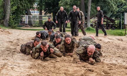 Soldiers from 278th Armored Cavalry Regiment along with Polish soldiers low crawl in the sand during day two of training for the Water Survival Course hosted by 15th Mechanized Brigade in Gizycko, Poland, Aug. 12, 2019.