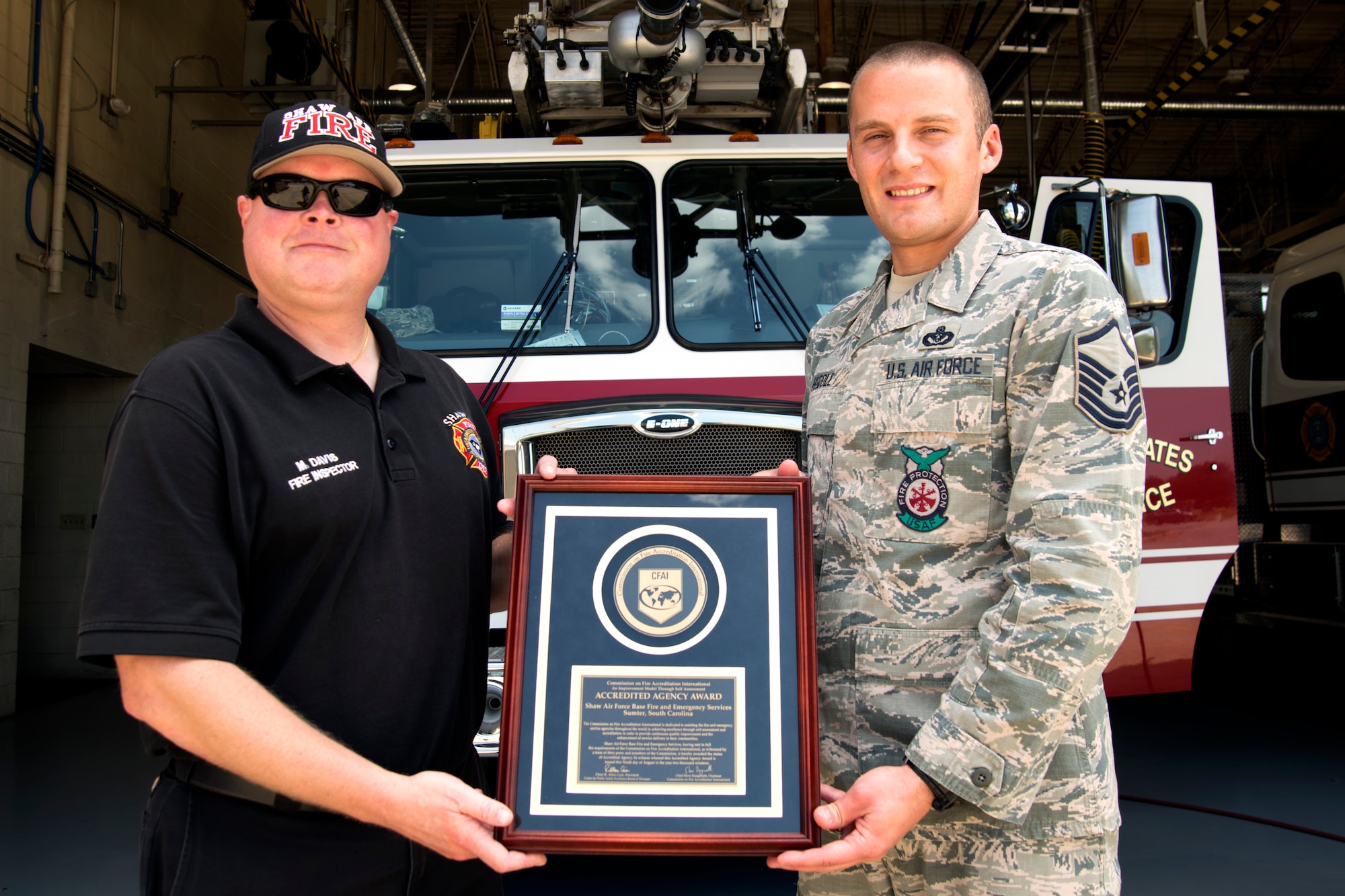 U.S. Air Force Master Sgt. Aaron Huddle, 20th Civil Engineer Squadron (CES) assistant fire protection chief, right, and Michael Davis, 20th CES fire inspector and accreditation manager, hold a Commission on Fire Accreditation International (CFAI) Accredited Agency Award at Shaw Air Force Base, South Carolina, Aug. 14, 2019.