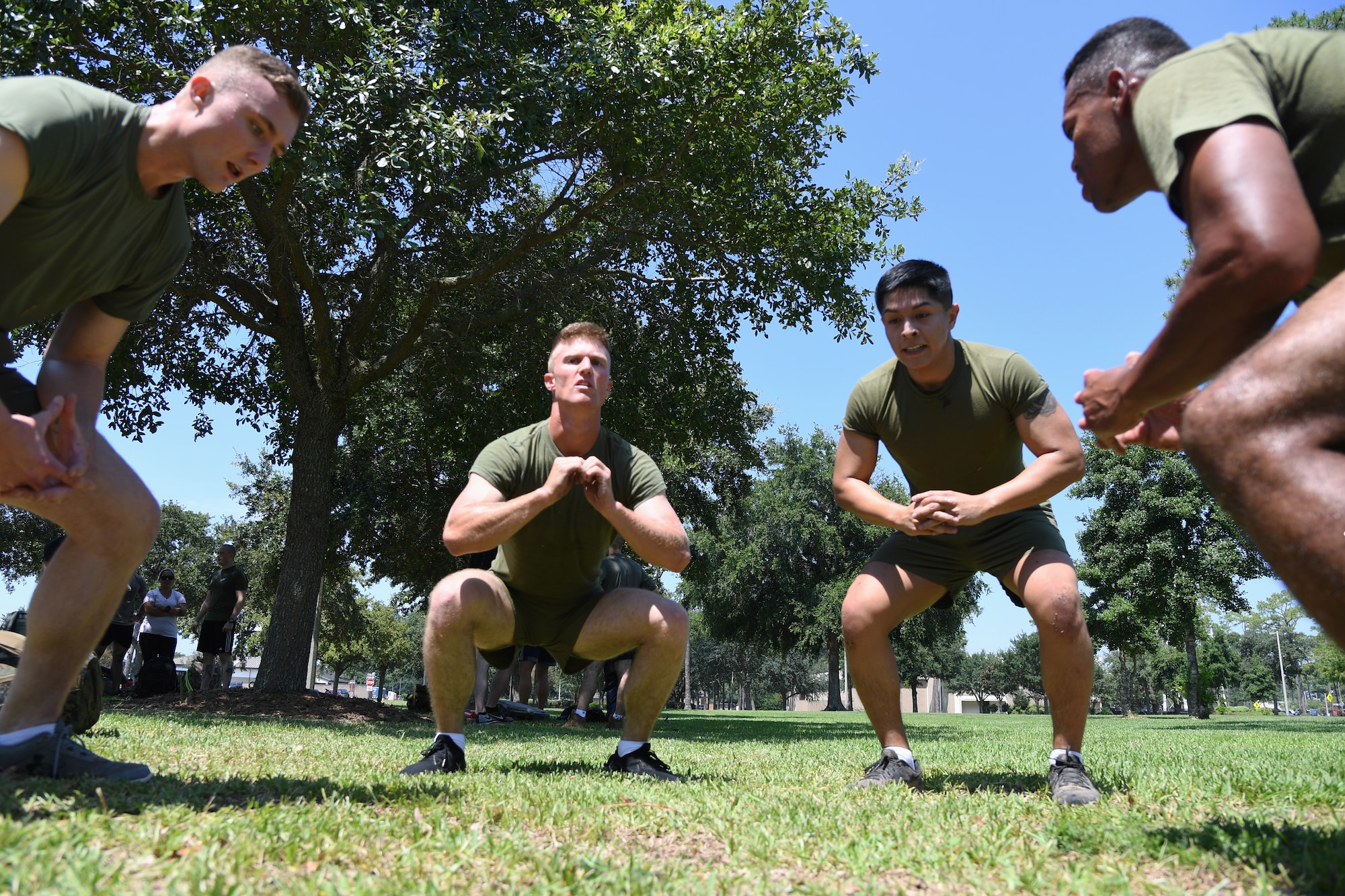 Members of the Keesler Marine Detachment team participate in the air squats portion of the 81st Security Forces Squadron Defender's Challenge Ruck near the Crotwell Track on Keesler Air Force Base, Mississippi, Aug. 16, 2019. The competition, consisting of 11 four-person teams, completing seven obstacles, was one of several events in recognition of The Year of the Defender. (U.S. Air Force photo by Kemberly Groue)