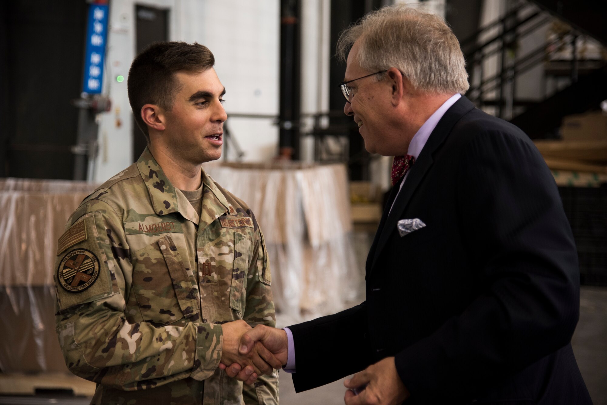 Christopher Cooper, branch head of Naval Sea Systems Command, hands Tyler Almquist, air freight flight commander, a challenge coin August 16, 2019, at Dover Air Force Base, Del. After many hurdles, the torpedo was delivered to India and was successfully launched from an Indian P-8 submarine hunter. (US Air Force Photo by Airman 1st Class Jonathan Harding)