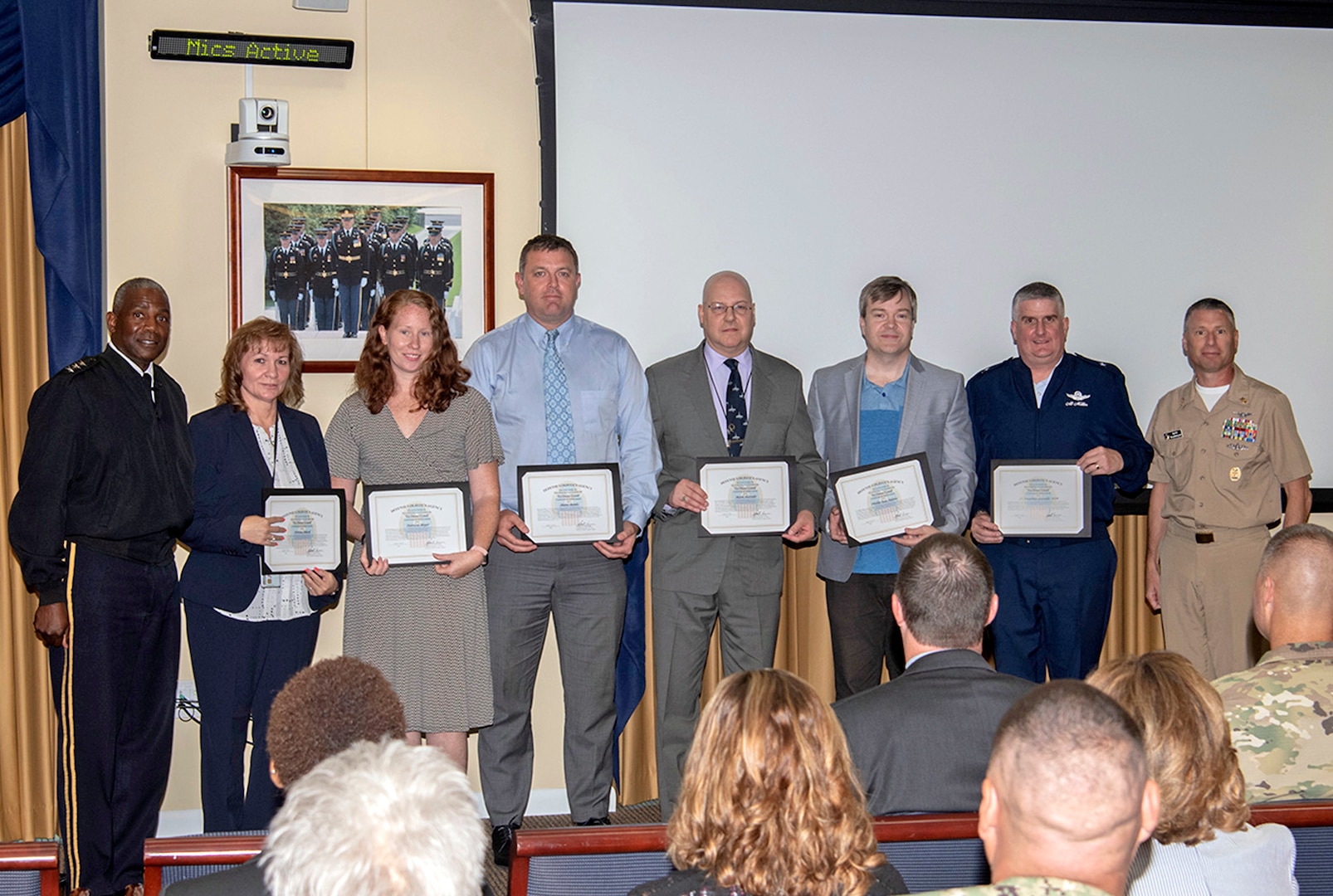 A line of employees holding award certificates