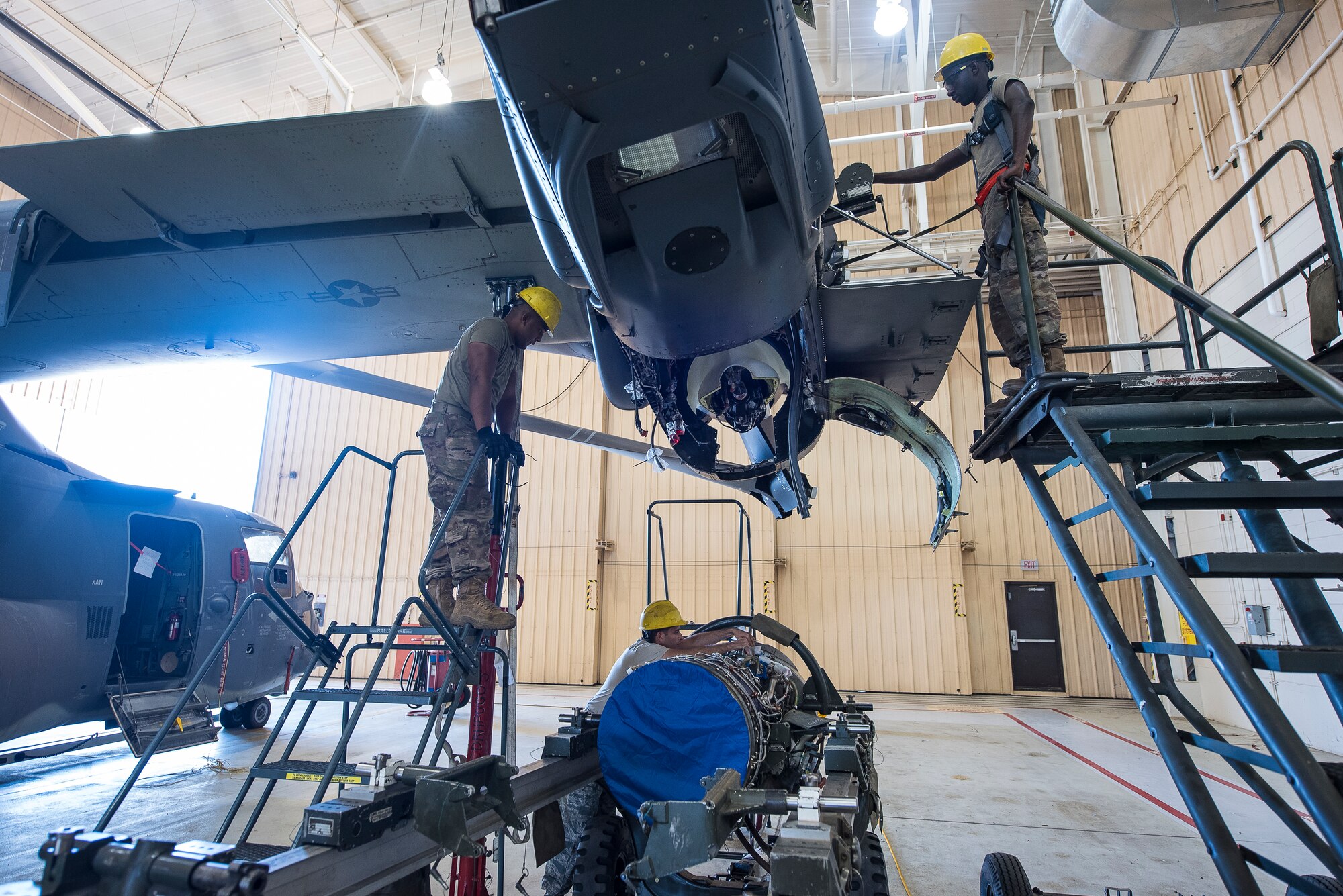 Members of the 727th Special Operations Aircraft Maintenance Squadron guide a CV-22 Osprey engine into position to be hoisted into the aircraft at Cannon Air Force Base, N.M, Aug. 13, 2019. The process of replacing the engine took the team of three 25 minutes. (U.S. Air Force Photo by Senior Airman Vernon R. Walter III)