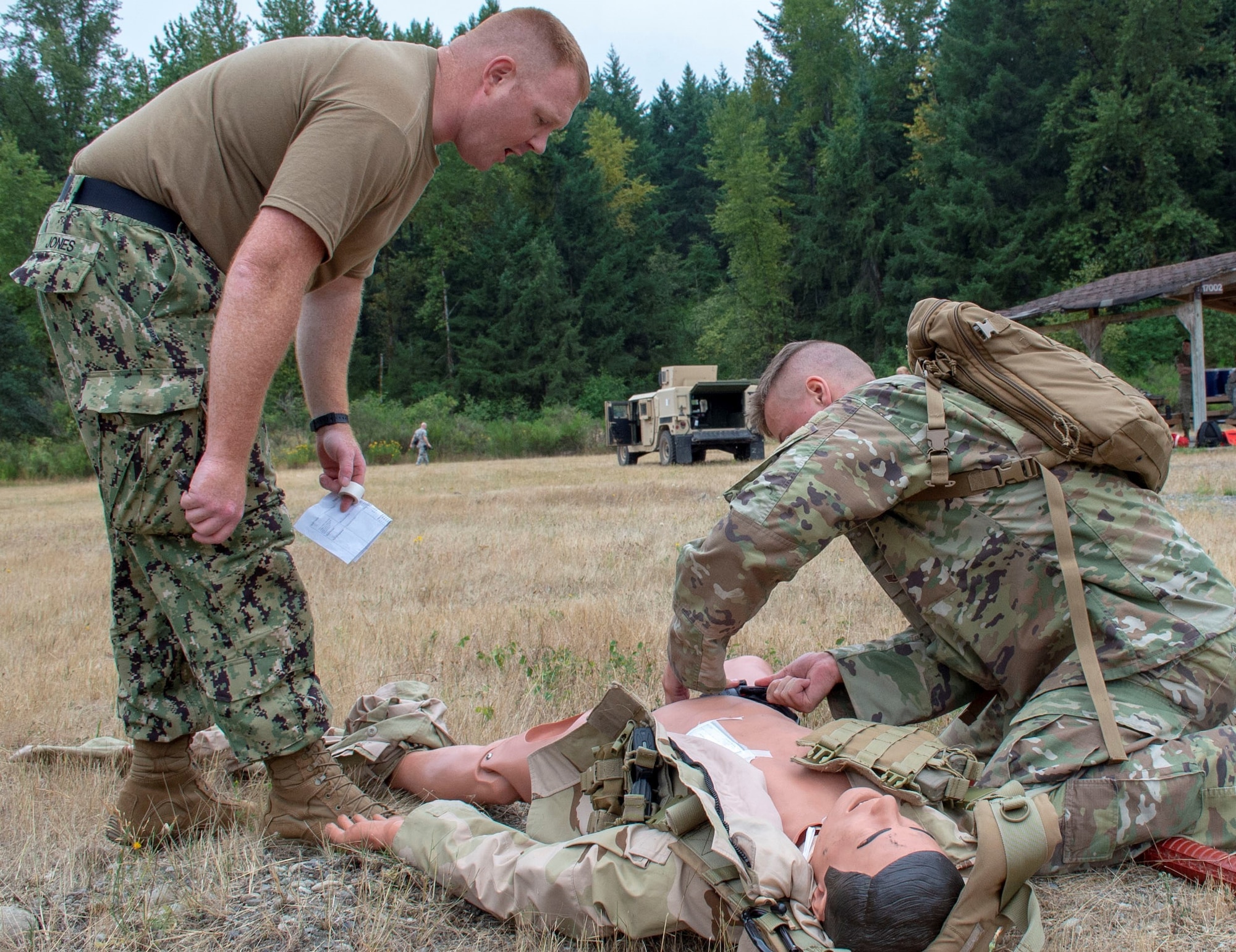Hospital Corpsman 1st Class Brian Jones, an instructor assigned to Navy Reserve Navy Medicine Education and Training Command and selected for the rank of chief, evaluates Air Force Staff Sgt. Connor Bitterman tending to a simulated casualty during a tactical combat casualty care (TCCC) class for exercise Tropic Halo 2019 at Joint Base Lewis-McChord in Tacoma, Wash., Aug. 7, 2019. Tropic Halo is designed to enhance Operational Hospital Support Unit Bremerton's medical and mission capabilities on several levels: increase TCCC and trauma nurse core course readiness rates; promote intra-service cohesion with collaborative training in a joint service environment and leverage Navy and U.S. Air Force command assets to generate better training opportunities. (U.S. Navy photo by Mass Communication Specialist 1st Class Ryan Riley)
