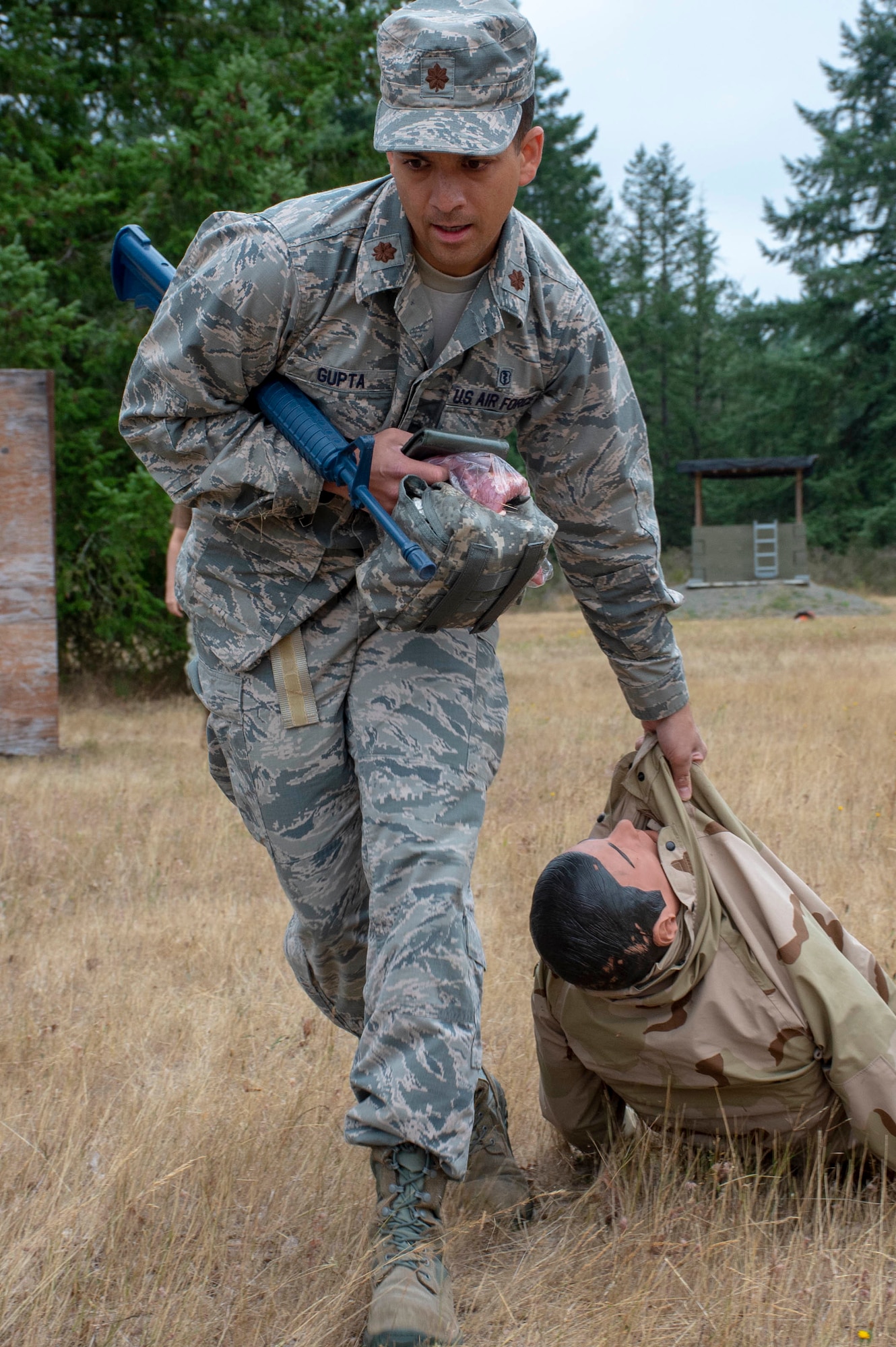 U.S. Air Force Maj. Vinay Gupta moves a simulated casualty during a tactical combat casualty care (TCCC) class for exercise Tropic Halo 2019 at Joint Base Lewis-McChord in Tacoma, Wash., Aug. 7, 2019. Tropic Halo is designed to enhance Operational Hospital Support Unit Bremerton's medical and mission capabilities on several levels: increase TCCC and trauma nurse core course readiness rates while minimizing overall training costs; promote intra-service cohesion with collaborative training in a joint service environment and leverage Navy and Air Force command assets to generate better training opportunities. (U.S. Navy photo by Mass Communication Specialist 1st Class Ryan Riley)