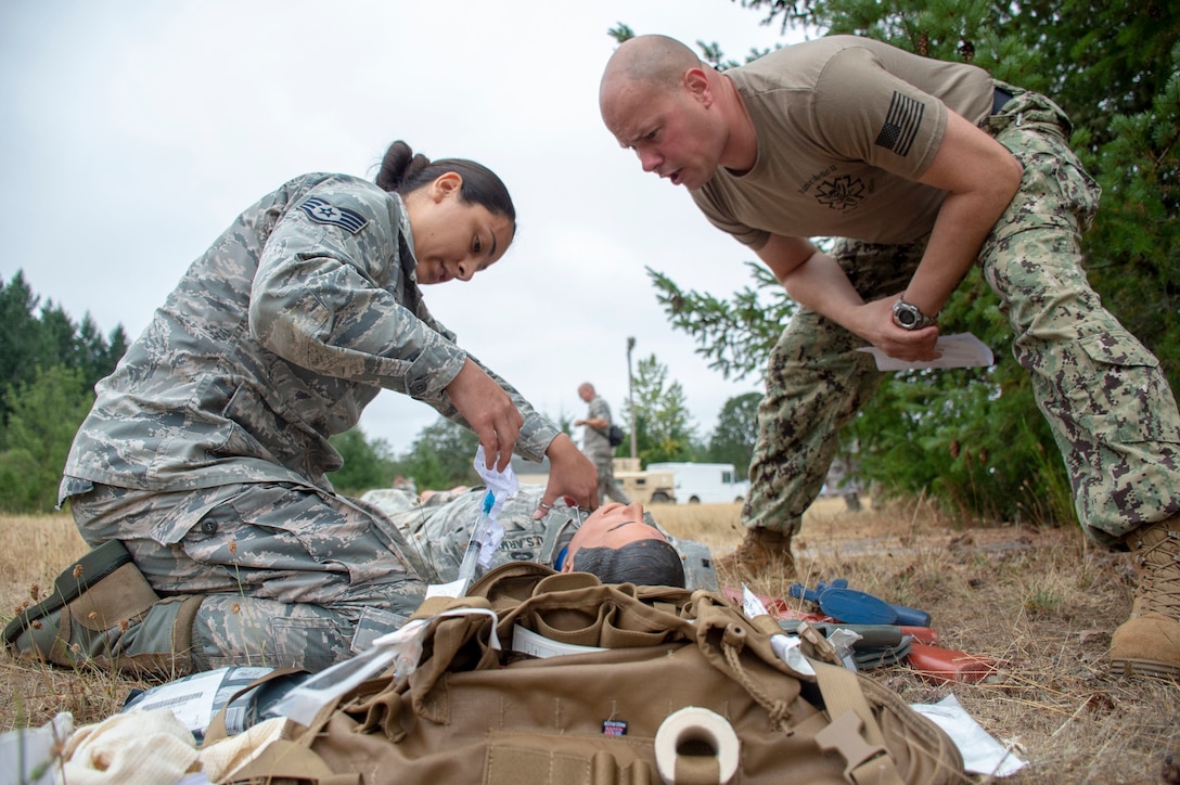 Hospital Corpsman 1st Class Rob Johnston, an instructor assigned to Navy Reserve Navy Medicine Education and Training Command and selected for the rank of chief, evaluates U.S. Air Force Staff Sgt. Mariela Rodriguez tending to a simulated casualty during a tactical combat casualty care (TCCC) class for exercise Tropic Halo 2019 at Joint Base Lewis-McChord in Tacoma, Wash., Aug. 7, 2019. Tropic Halo is designed to enhance Operational Hospital Support Unit Bremerton's medical and mission capabilities on several levels: increase TCCC and trauma nurse core course readiness rates while minimizing overall training costs; promote intra-service cohesion with collaborative training in a joint service environment and leverage Navy and Air Force command assets to generate better training opportunities. (U.S. Navy photo by Mass Communication Specialist 1st Class Ryan Riley)