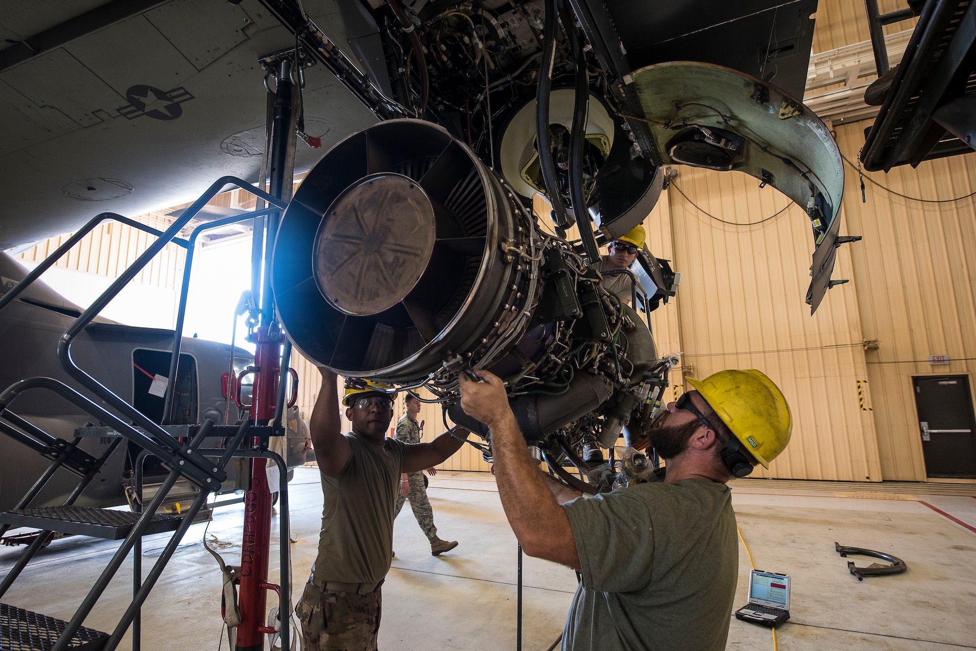 Airman 1st Class Omar Rodriguez, 727th Special Operations Aircraft Maintenance Squadron crew chief, and Luke McSweeney, 727 SOAMXS contract maintainer, guide a CV-22 Osprey engine into the aircraft as it is hoisted at Cannon Air Force Base, N.M, Aug. 13, 2019. The process of replacing the engine took the team of three 25 minutes. (U.S. Air Force Photo by Senior Airman Vernon R. Walter III)