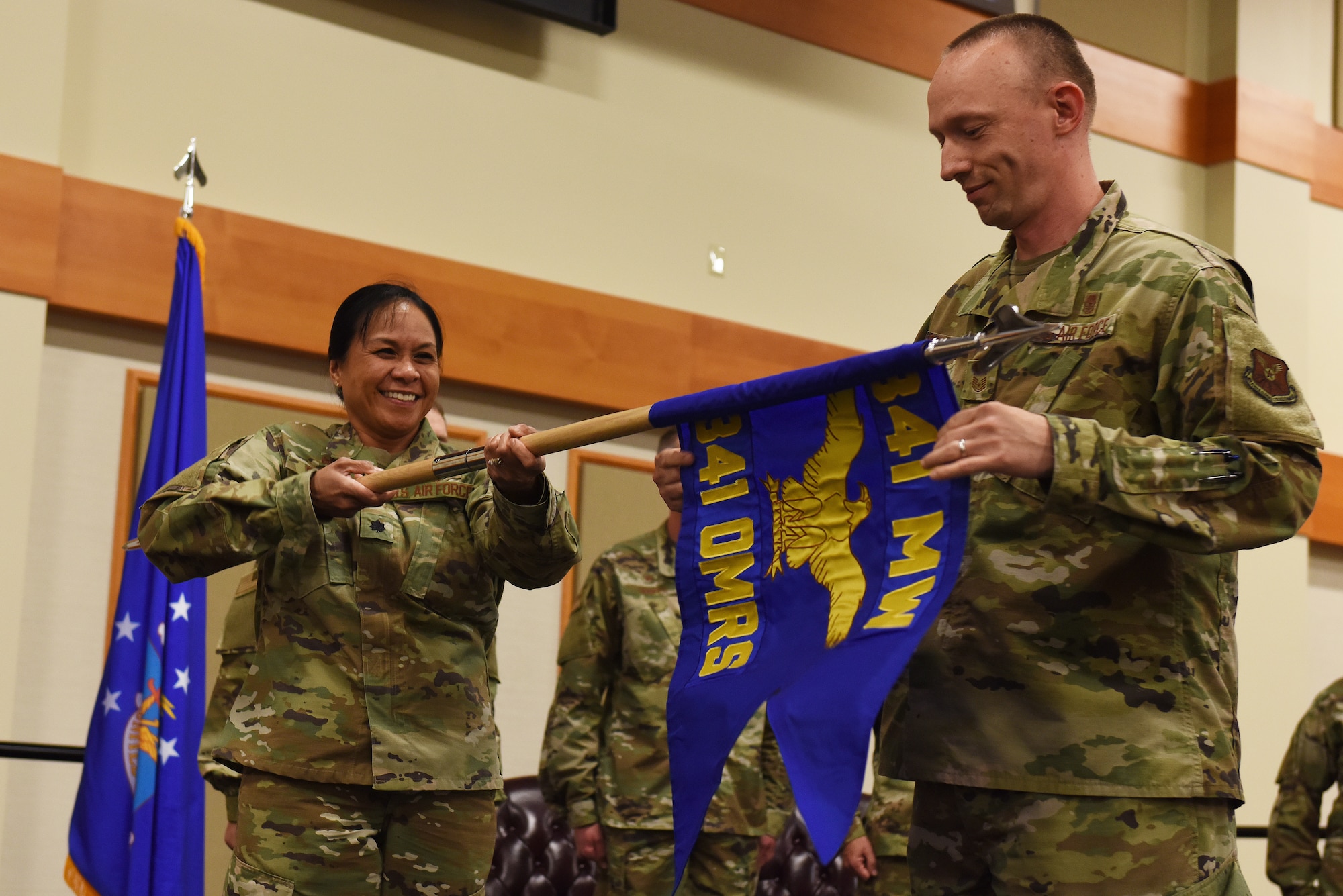 Lt. Col. Michelle Dimoff, 341st Operational Medical Readiness Squadron commander, left, and Master Sergeant Derrick Rutherford, 341st OMRS superintendent, unfurl the OMRS guidon August 16, 2019, at the Grizzly Bend on Malmstrom Air Force Base, Mont.