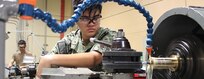 Machinery Repairman 3rd Class Patrisha Castro using a lathe manufactures a hose adapter for the Diesel Shop