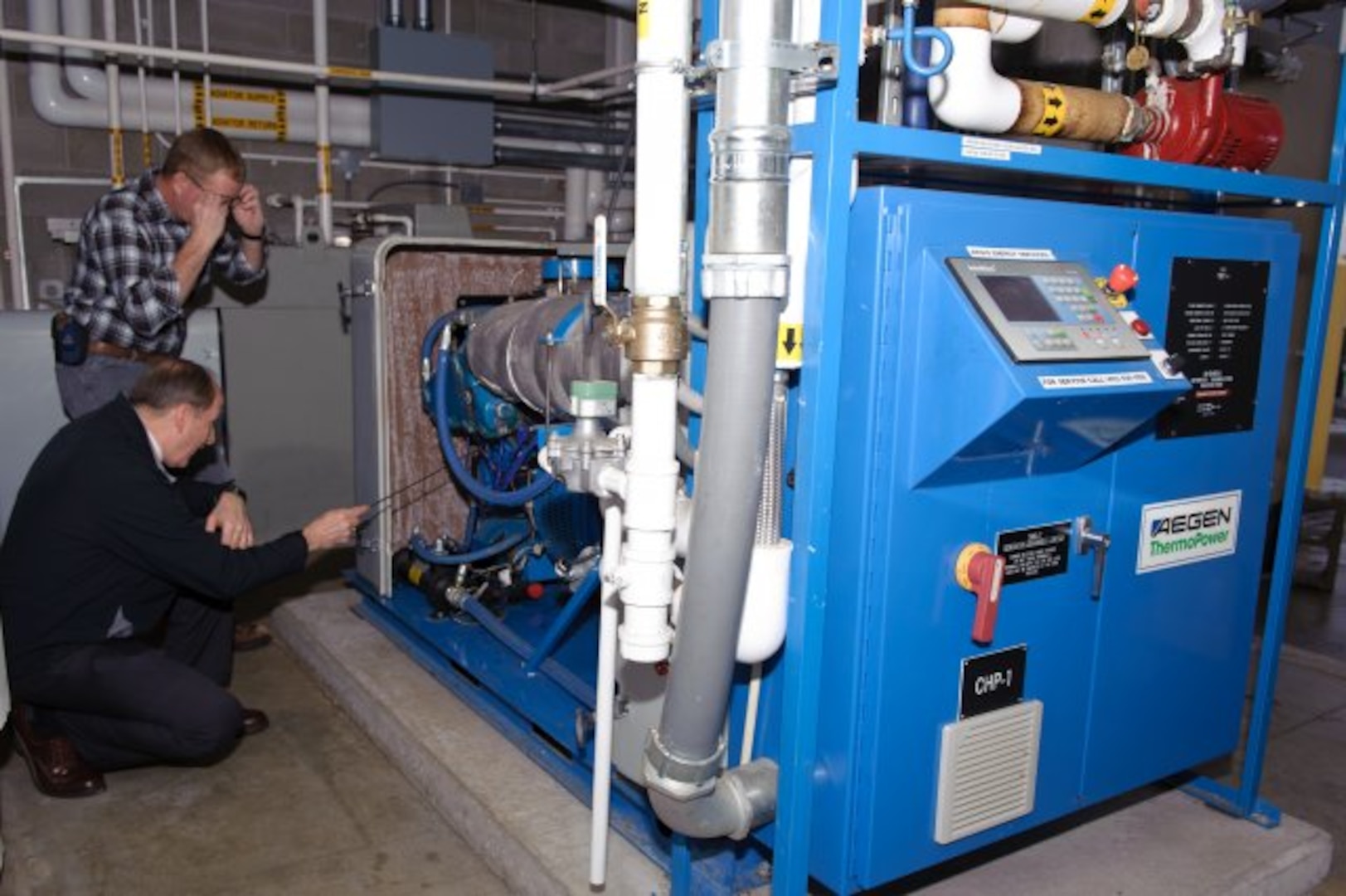 A.J. Ballard, the energy manager for the Maine Army National Guard points out some of the engine details of the award-winning combined heat and power system at the Maine Army National Guard Army Aviation Support Facility in Bangor, Maine. "This is a wonderful machine," said Ballard. "This system produces electricity we don't have to pay for, and heat we don't have to pay for."