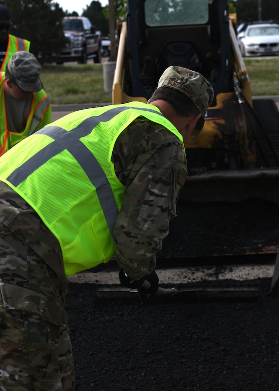 Col. Thomas Falzarano, 21st Space Wing commander, helps the 21st Civil Engineer Squadron pavement and heavy equipment operator Airmen, better known as the “Dirt Boyz,” spread asphalt evenly across a pothole Aug. 7, 2019, on Peterson Air Force Base, Colorado. Falzarano also learned how to properly seal and compress the patch of asphalt with a roller.  (U.S. Air Force photo by Airman 1st Class Andrew Bertain)