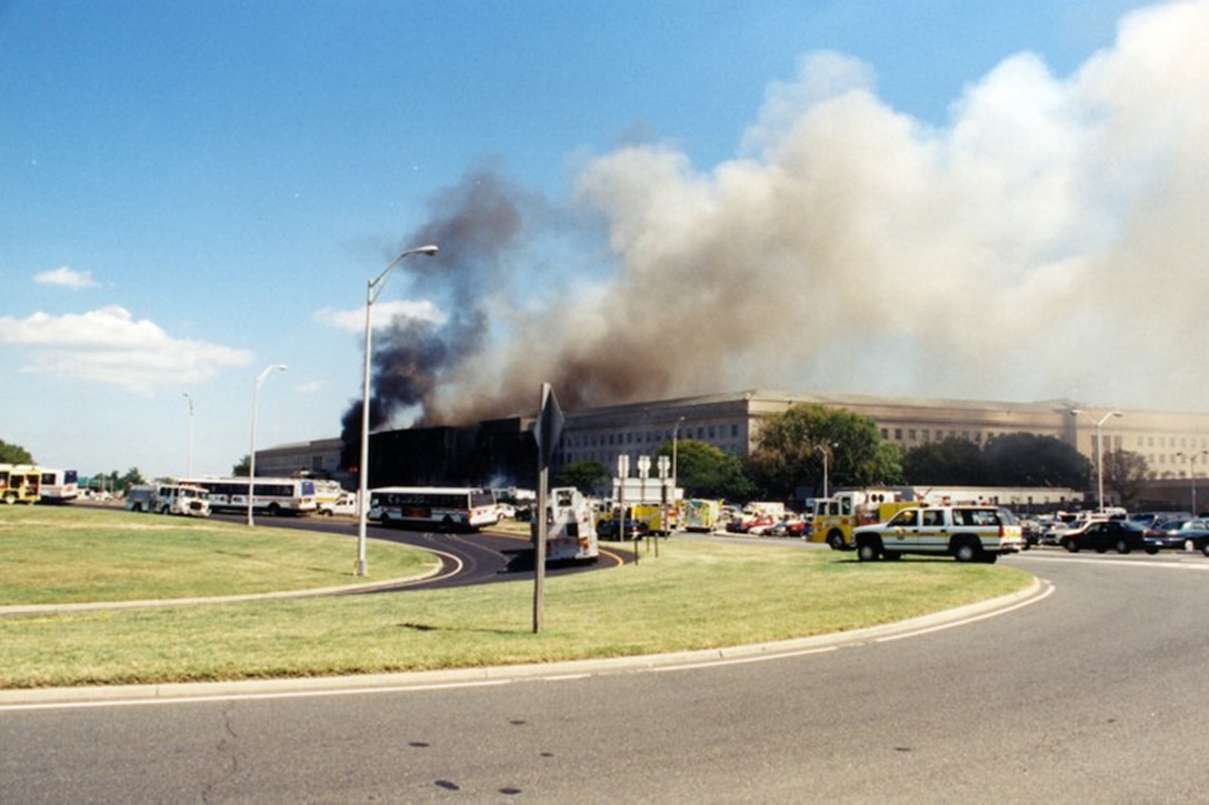 Smoke pours out of the Pentagon as emergency response vehicles surround the building.