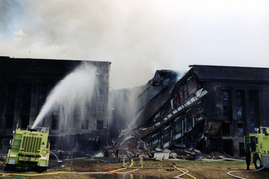 Emergency response vehicles spray water onto the damaged Pentagon wall.