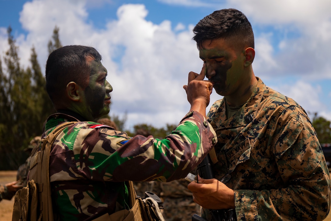 A U.S. Navy Corpsman with Alpha Company, 1st Battalion, 3rd Marine Regiment, and an Indonesian Korps Marinir (KORMAR) apply camouflage paint before patrol operations at Kahuku Training Area, Aug. 13, 2019. This training is part of a military exchange program designed to strengthen the partnership between the two militaries. The KORMAR exchange enhances the capability of both services and displays their continued commitment to share information and increase the ability to respond to crises together. (U.S. Marine Corps Photo by Cpl. Brendan Custer)