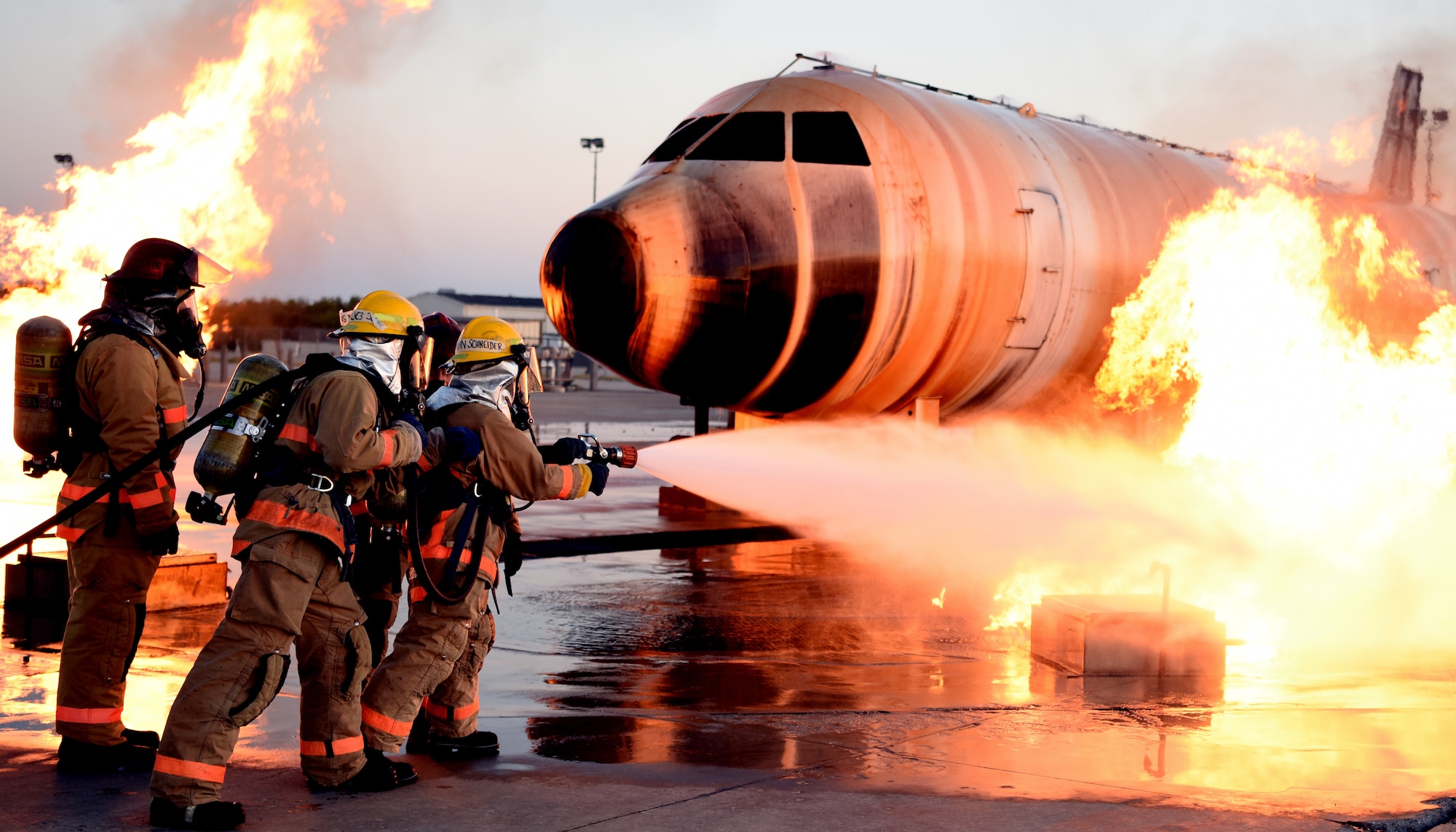 U.S. Air Force Airman Kristina Schneider, 312th Training Squadron student, approaches an exterior aircraft fire with a water hose outside the Louis F. Garland Department of Defense Fire Academy on Goodfellow Air Force Base, Texas, August 16, 2019. Though Schneider has graduated three fire academies throughout her civilian firefighting career, she expands her knowledge with aircraft fire suppression during her technical school training at Goodfellow.  (U.S. Air Force photo by Airman 1st Class Ethan Sherwood/Released)