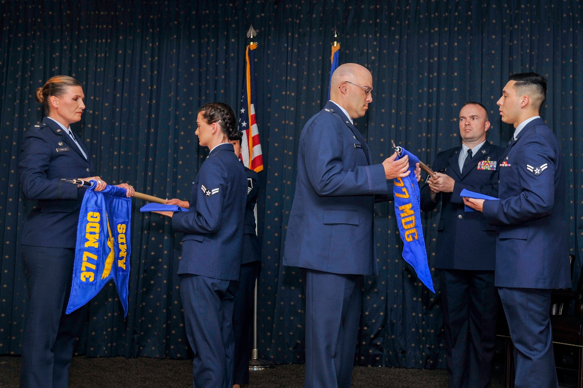 Guidons belonging to the 377th Aerospace Medicine Squadron and the 377th Medical Operations Squadron are furled in a redesignation ceremony at Kirtland Air Force Base, N.M., August 16, 2019. The 377th Aerospace Medicine Squadron and the 377th Medical Operations Squadron were redesignated to the 377th Operational Medical Readiness Squadron and the 377th Healthcare Operations Squadron respectively. (U.S. Air Force photo by Airman 1st Class Austin J. Prisbrey)